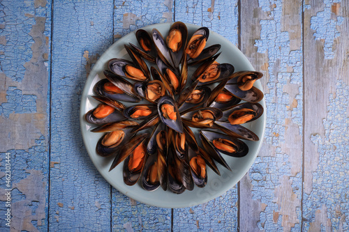 Portion of cooked Galician mussels on blue old wooden background