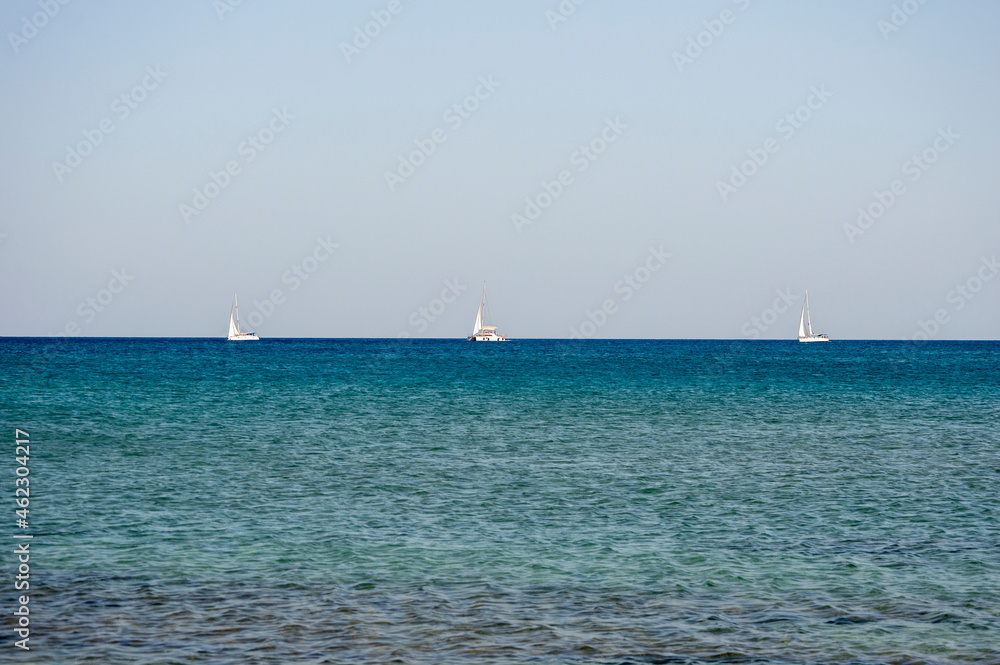 3 White boats sailing in the open blue aegean sea in Greece