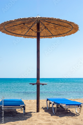 Fototapeta Naklejka Na Ścianę i Meble -  Two sun beds under sun umbrella at the beach. Zephyros beach. Greece