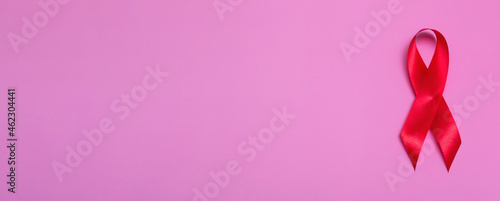 Top view on pink background with red ribbon concept December 1st International AIDS Day close-up.