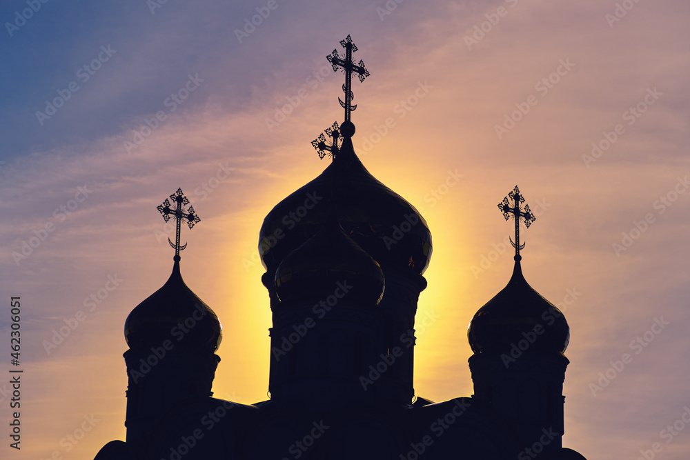 The silhouette of an Orthodox church with crosses on the domes. sunrise at the religious building