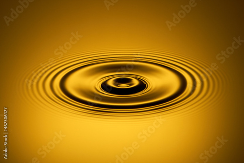 Water drop created ripples on the surface of the golden water.