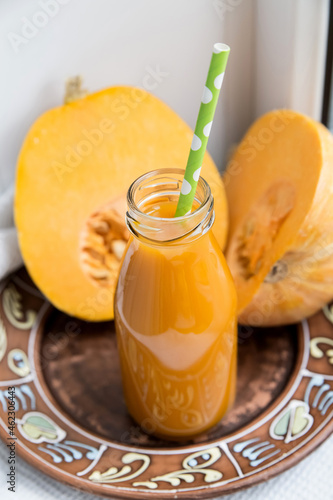 Pumpkin juice in a bottle light background, pumpkin