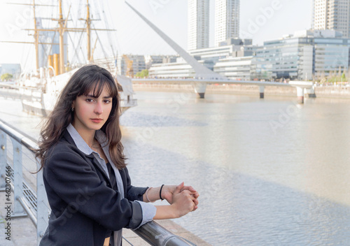 young woman on a wharf by the river with a frigate behind her