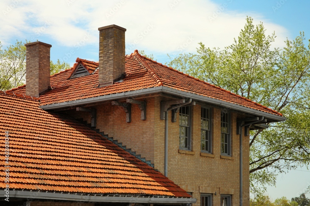 Sloping paneled roof on old brick house with two chimneys