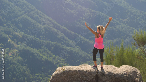 Rapariga a fazer terapia de bem estar em cima de uma pedra no topo de uma montanha, viagem, equilíbrio, em posição de exercício de yoga