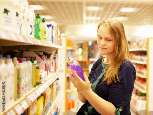 Canvastavla Young woman in the supermarket reading inscription