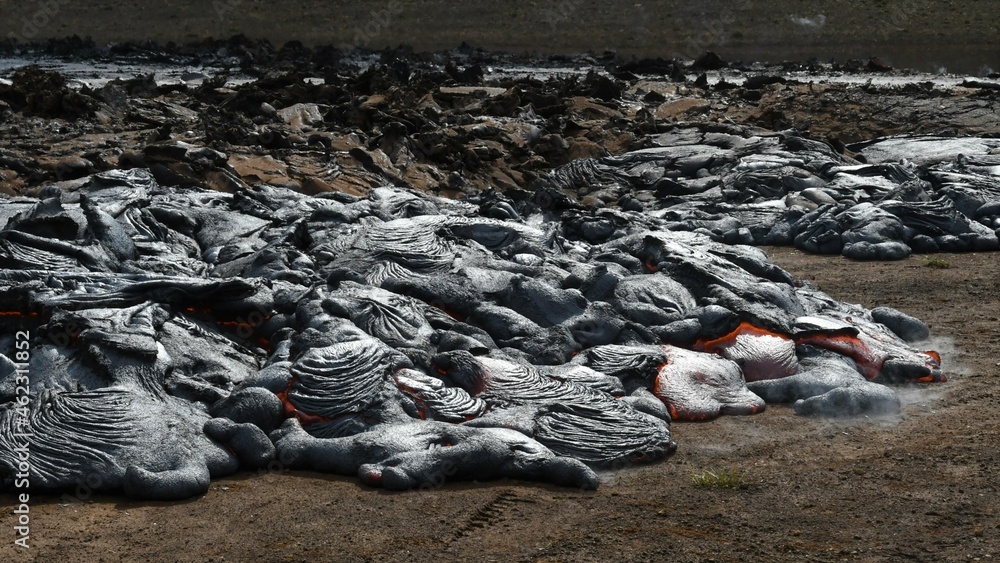Pahoehoe lava flow at Fagradalsfjall, Iceland. Lava crust is gray and black, molten lava is red and orange. Steam and gas are visible. Pahoehoe lava flow at Fagradalsfjall, Iceland. Lava crust is gray and black, molten lava is red and orange. Steam and gas are visible.