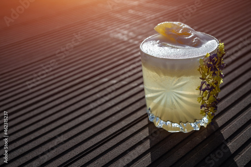 margarita pineapple cocktail in glass garnished flower on wooden background photo