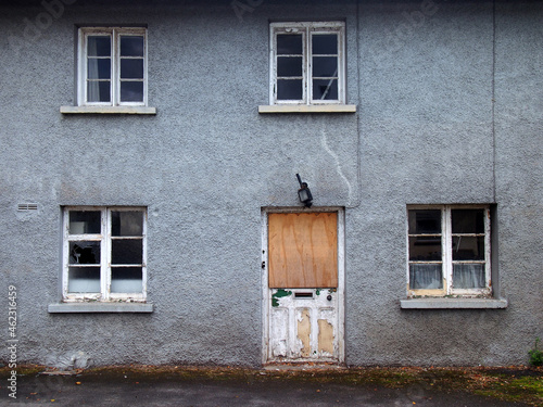 Canvas Print an old abandoned grey derelict house on a residential street with dirty broken w