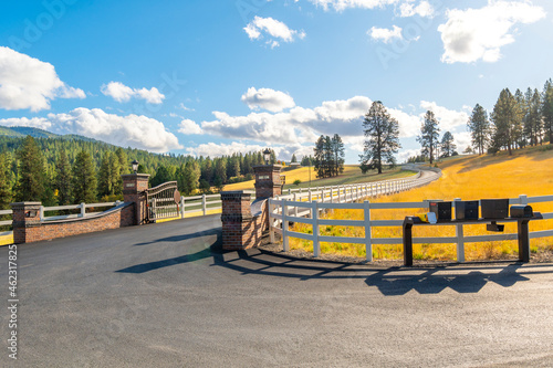 Obraz na plátně A winding gated road or path with white fence in a rural community of luxury homes on acreage at autumn in the Saltese Uplands and Flats area of Spokane, Washington, USA