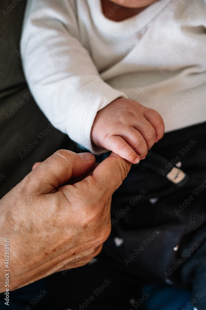 Close up of baby holding grandmother's finger