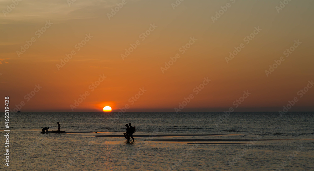 Tourists walking at sunset in the middle of the sea at low tide on this paradisiacal island called Holbox, located in Mexico.