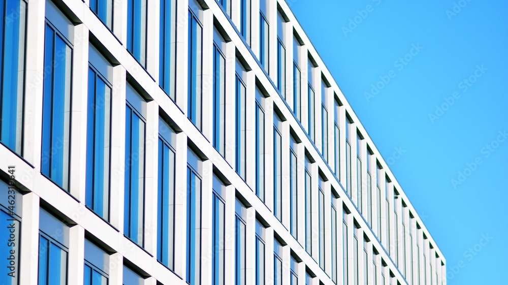 Modern office building with glass facade on a clear sky background. Transparent glass wall of office building. Modern office building with glass facade on a clear sky background. Transparent glass wall of office building.