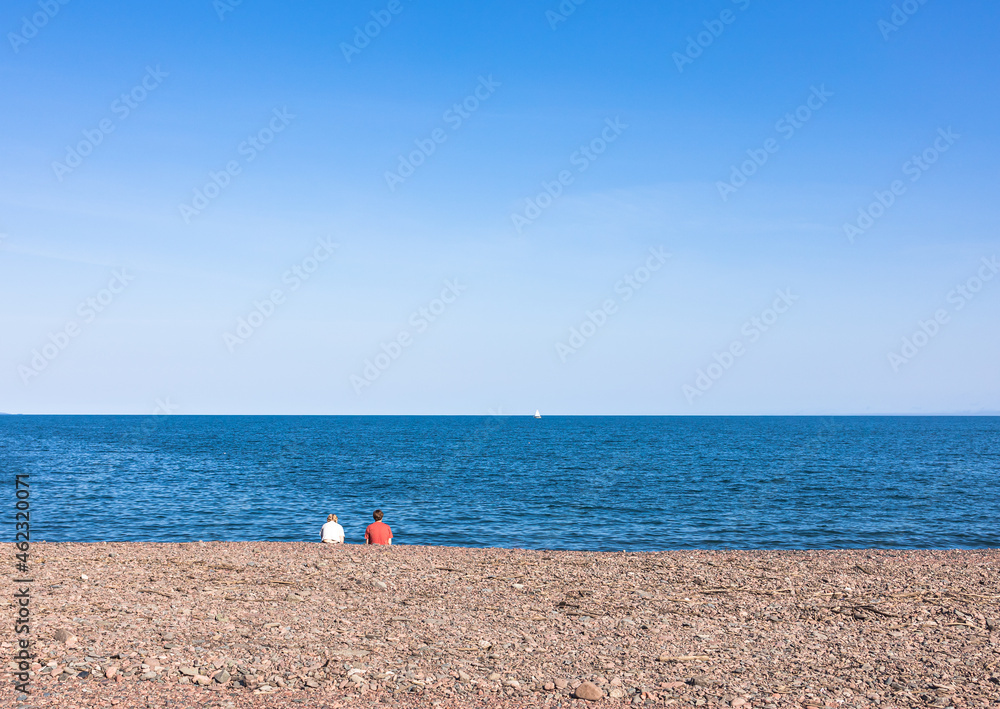 Young couple sitting on the beach at seascape view Young couple sitting on the beach at seascape view