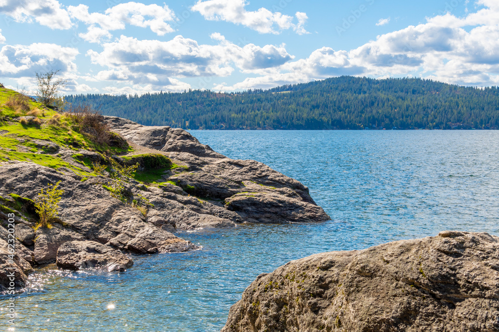 View of the lake and mountains from the beach and shoreline of Tubbs Hill park in Coeur d'Alene, Idaho, USA.