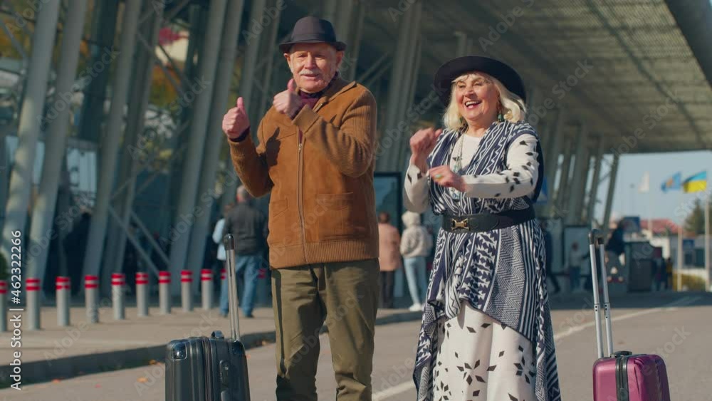 Elderly old husband and wife retirees tourists dancing disco fooling around having fun expressive gesticulating hands near airport terminal. Lovely mature couple grandmother grandfather celebrating Elderly old husband and wife retirees tourists dancing disco fooling around having fun expressive gesticulating hands near airport terminal. Lovely mature couple grandmother grandfather celebrating