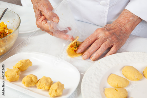 Preparation of the traditional patties from the region of Cauca in Colombia, called empanadas de pipián - Senior woman filling the patties