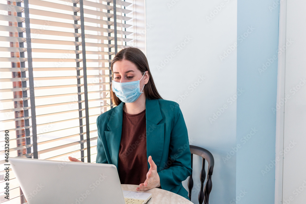 Young woman in suite with protective mask is working on computer.
