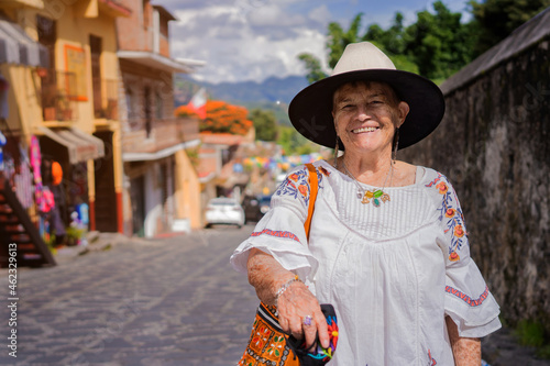 Mexican grandmother smiling at the camera. adult latina with sombrero on a sunny day.