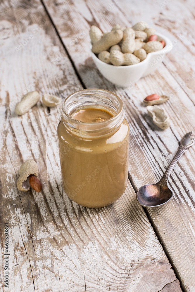Peanut butter in a glass jar on a wooden background. Delicious and healthy breakfast. Peanut butter in a glass jar on a wooden background. Delicious and healthy breakfast.