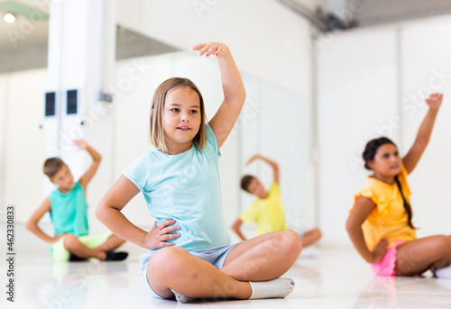 Children exercising during yoga class in fitness center - vakrasana pose