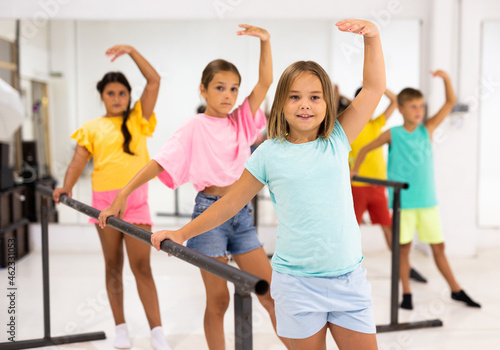 Youth girls and boys training ballet moves in studio.