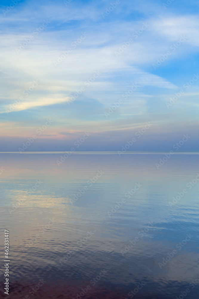 Beautiful sunset on sea, pastel colors and reflections on water, calm nature landscape with colorful clouds