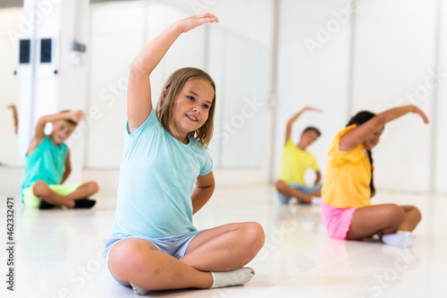 Group of emotional children doing yoga in a dance studio