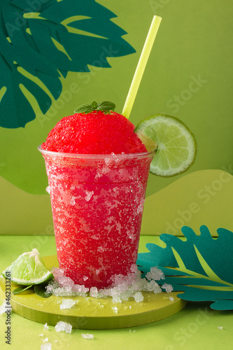 фотографія Strawberry and lemon slush in compostable glass on green background and green straw