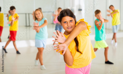 Positive girl exercising in group of classmates during dance class at school