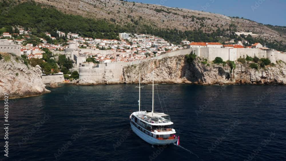 Pleasure Boat Cruising At Adriatic Sea Near Walls of Dubrovnik in Croatia. - aerial Pleasure Boat Cruising At Adriatic Sea Near Walls of Dubrovnik in Croatia. - aerial