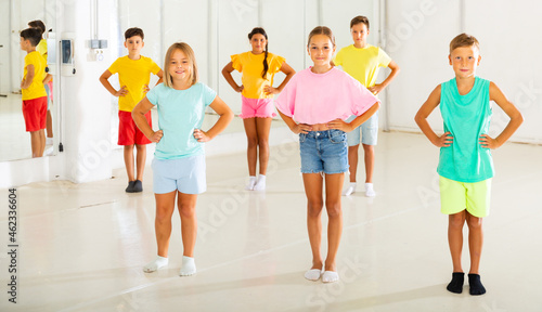 Young boys and girls standing with hands on their waists in dance studio.