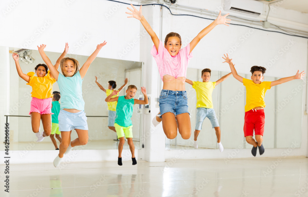 Happy children jumping while studying modern style dance in class indoors