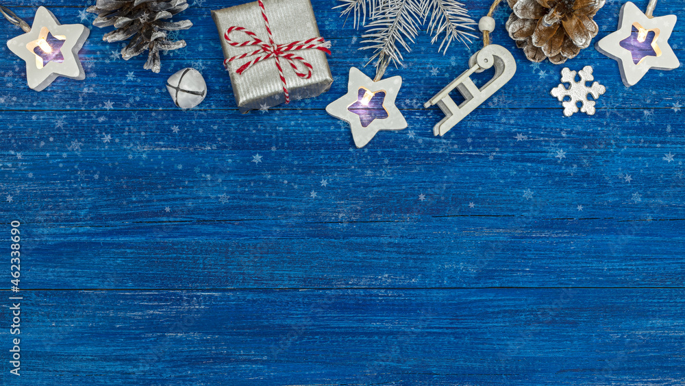 christmas ornaments with gift box, fir branch and star holiday lights on blue wooden background
