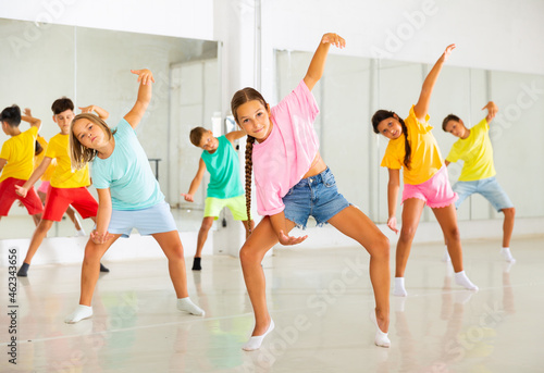 Portrait of modern tween girl krump dancer in choreographic studio with dancing children in background.