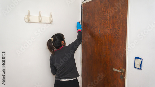 Young latin woman painting with a small brush a wall in her apartment