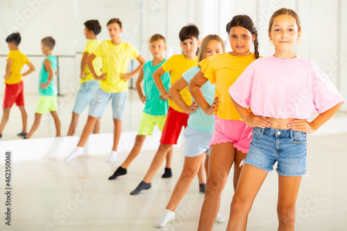 Group of positive children rehearsing movements of ballet in classroom