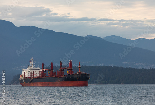 Old big cargo ship on the background of mountains. Oil tanker anchored in a sea.