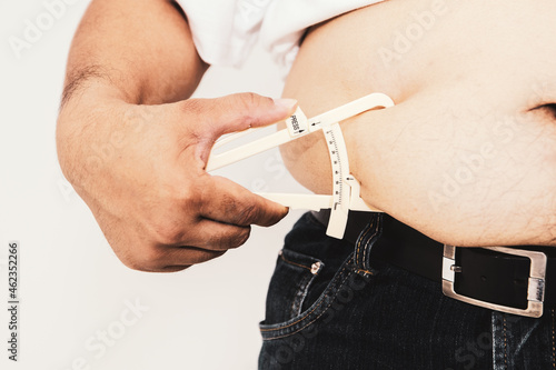 Closeup fat man using Fat Caliper Manual. Body fat measuring device by clamping on the skin.