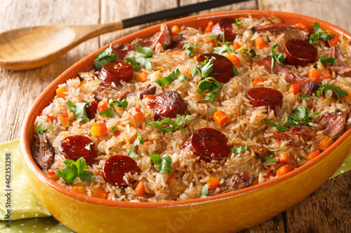 Portuguese duck rice arroz de pato cooked with red wine, onion, carrot and chorizo close up in the baking dish on the wooden table. Horizontal