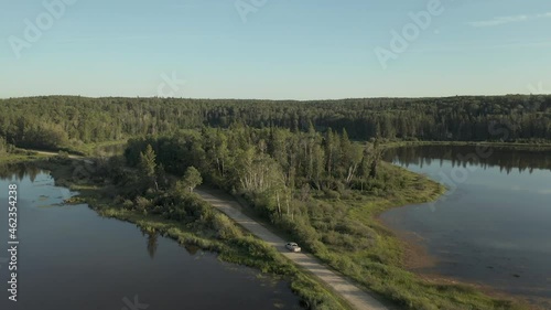 Truck And Car Driving On The Road Through Lakes In Boreal Forest, Saskatchewan, Canada. aerial photo