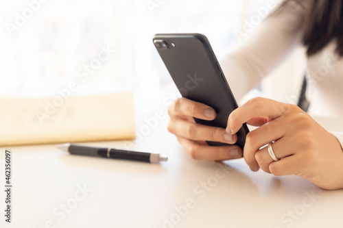 woman hands holding smartphone with notepad and pen in backlight