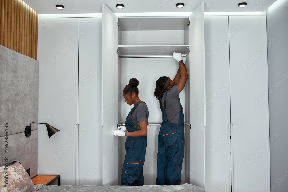 Workers mounting metal hanging rails in white wardrobe Workers mounting metal hanging rails in white wardrobe
