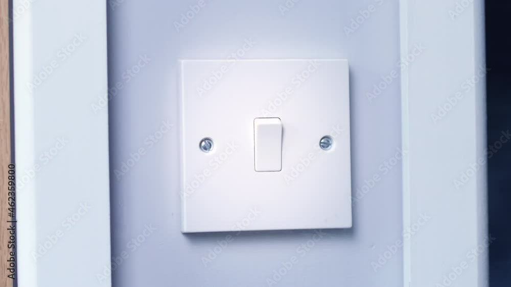 A light switch being turned on at night in a dark room A light switch being turned on at night in a dark room