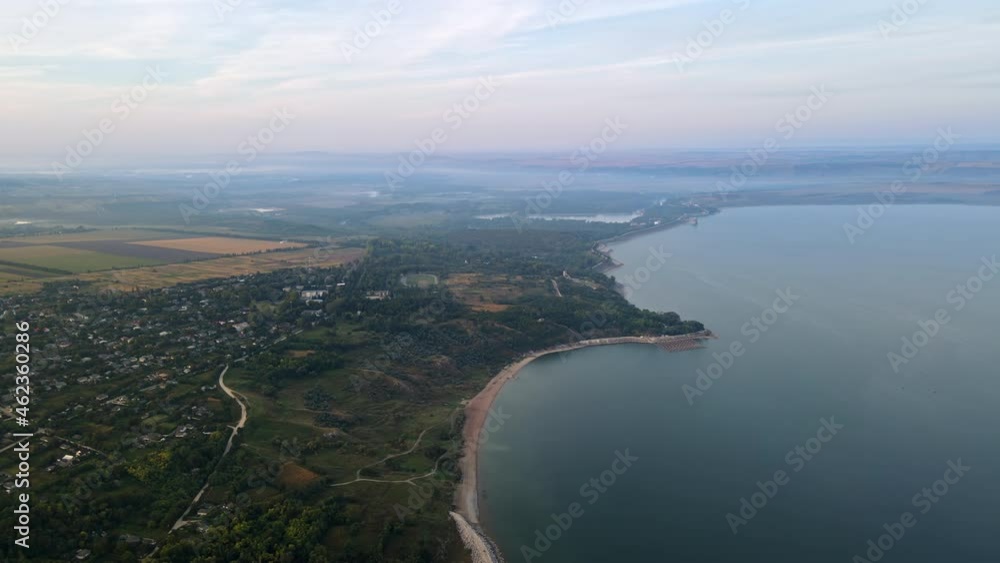 Aerial drone view of the Duruitoarea natural reservation in Moldova. River and fog in the air, hills and fields, village with roads and greenery Aerial drone view of the Duruitoarea natural reservation in Moldova. River and fog in the air, hills and fields, village with roads and greenery