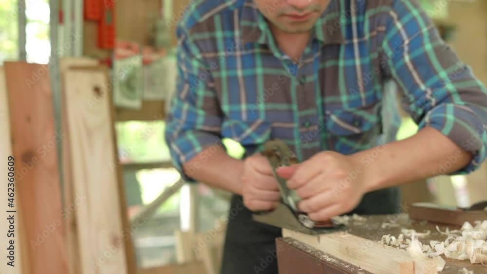 Carpenter concept . Asian man who owns a small lumber business is preparing wood for furniture production. carpenter is adjusting the surface of the wood to the desired size. Carpenter concept . Asian man who owns a small lumber business is preparing wood for furniture production. carpenter is adjusting the surface of the wood to the desired size.