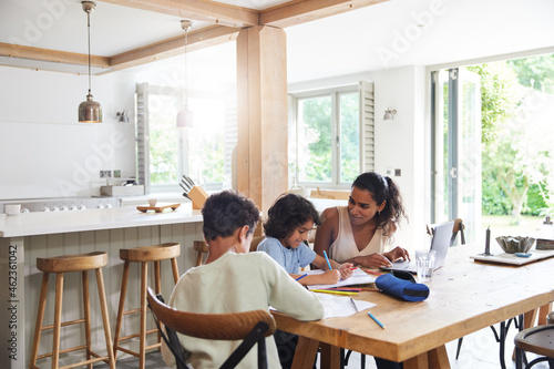 Mother with sons doing homework in kitchen