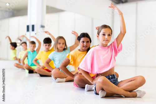Children exercising during yoga class in fitness center - vakrasana pose photo