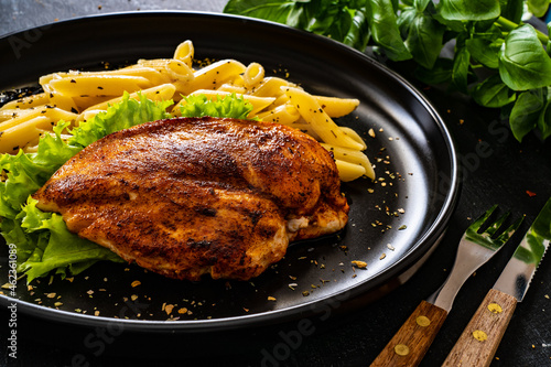 Fried chicken breast with pasta and vegetables on wooden background 